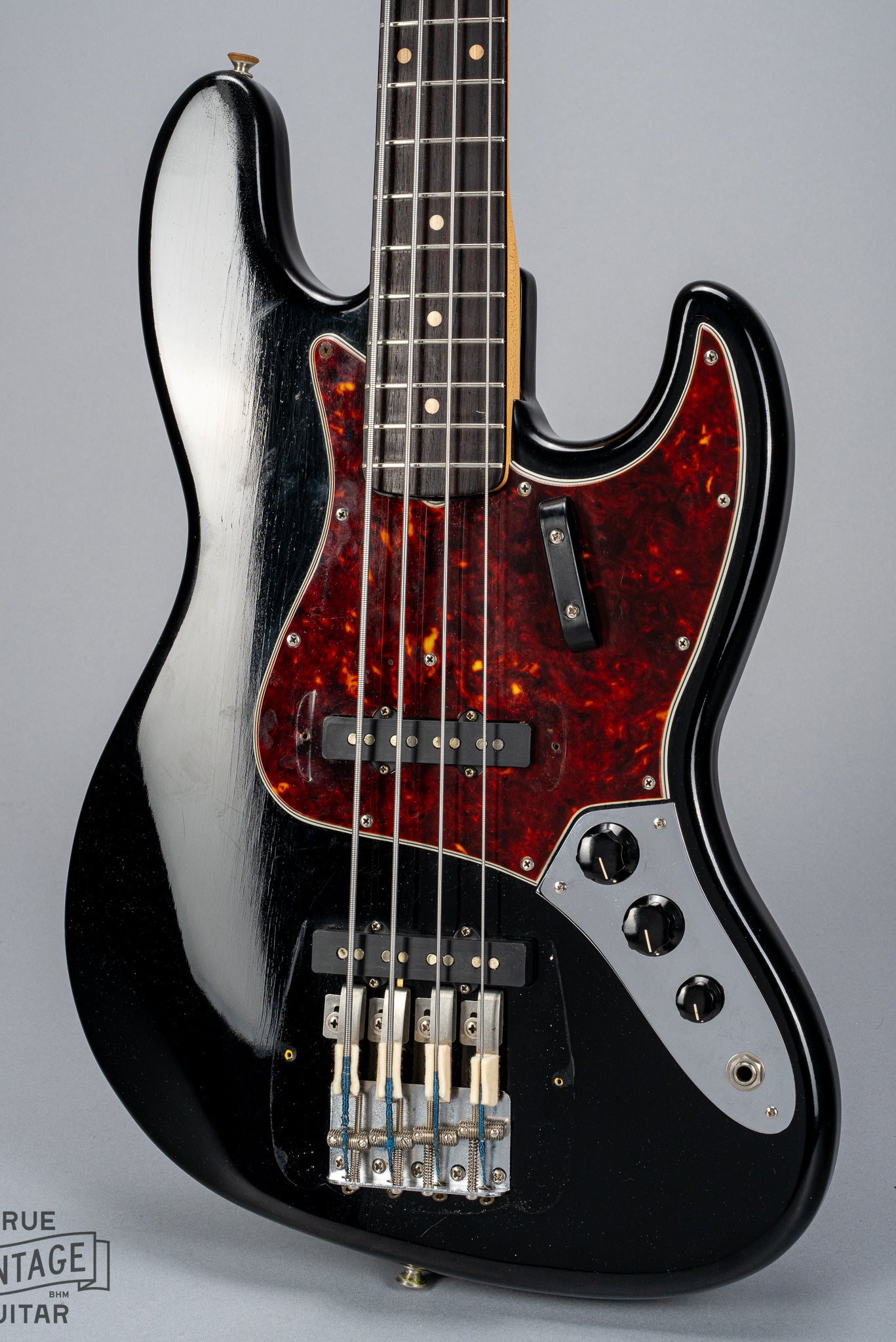 Front of 1962 Fender Jazz Bass custom color black custom color guitar tortoise shell pick guard no bridge and pickup cover finish checking