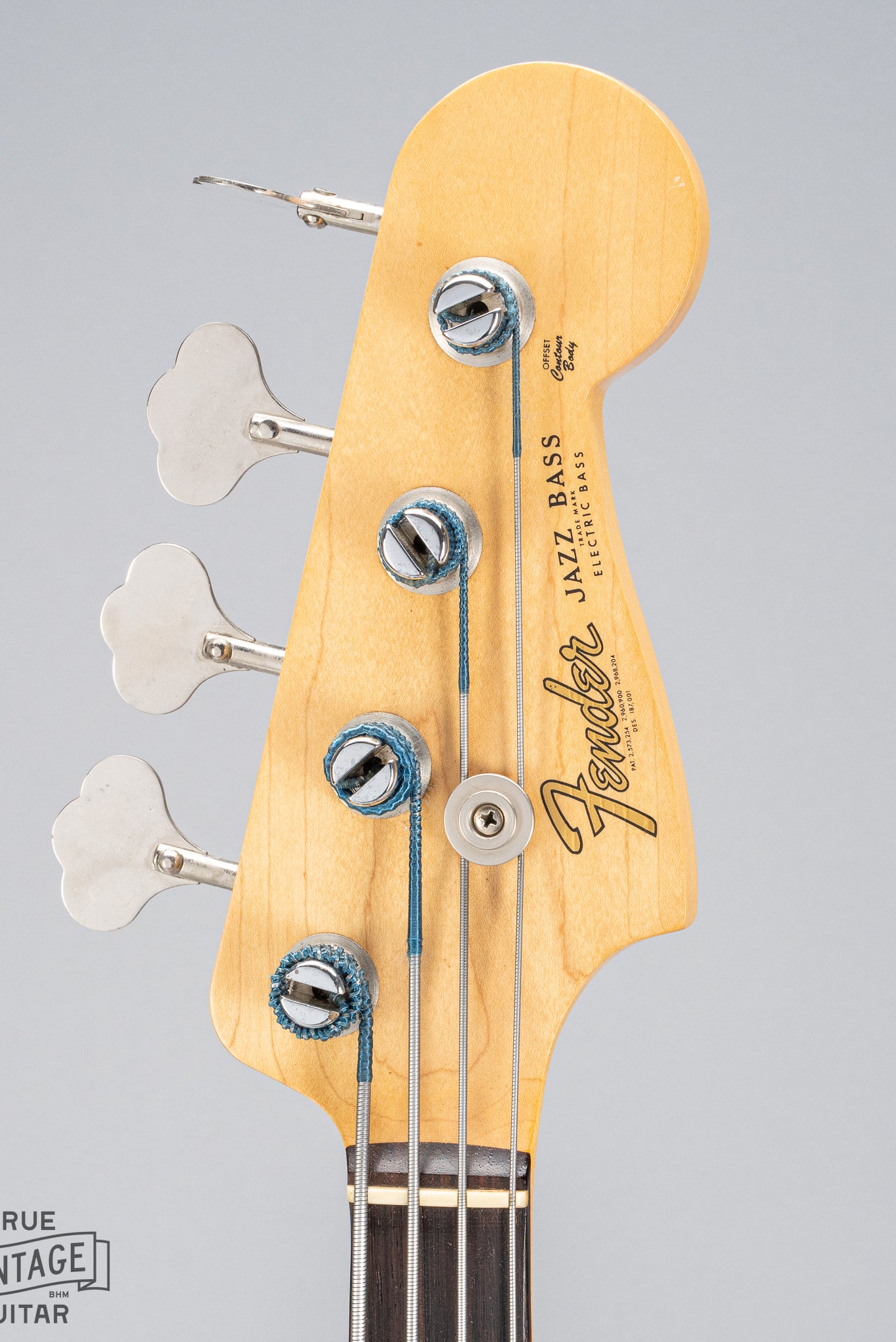 Front of 1962 Fender Jazz Bass custom color black custom color guitar HEadstock tuners Fender logo and print silk wrapped strings