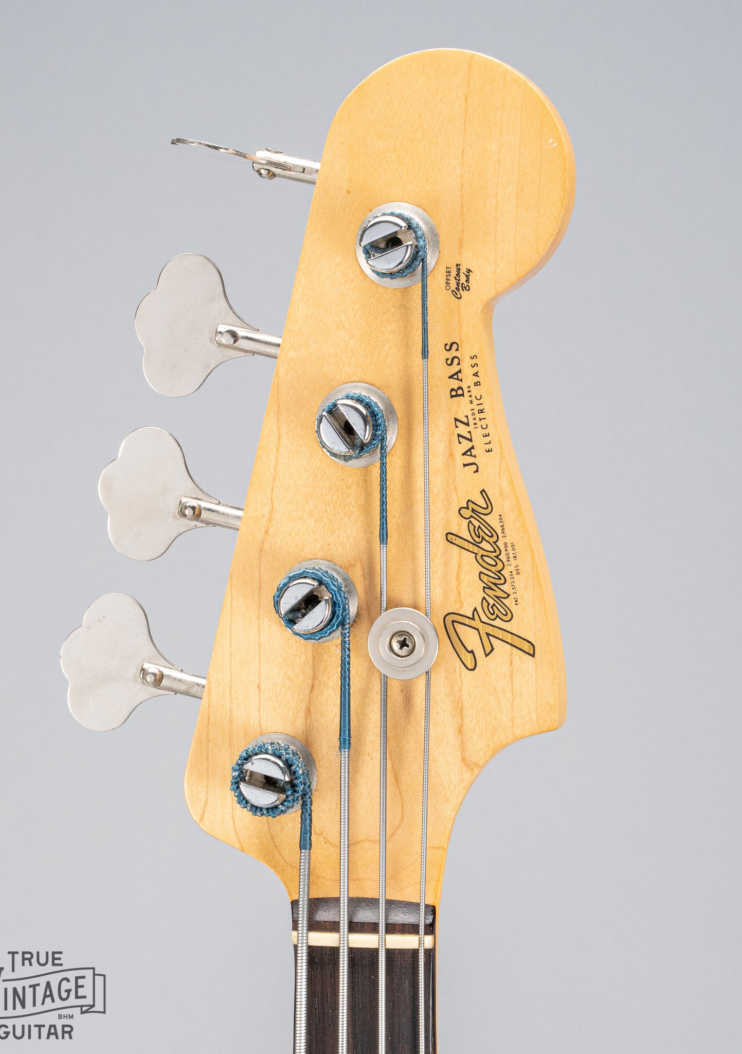 Front of 1962 Fender Jazz Bass custom color black custom color guitar HEadstock tuners Fender logo and print silk wrapped strings