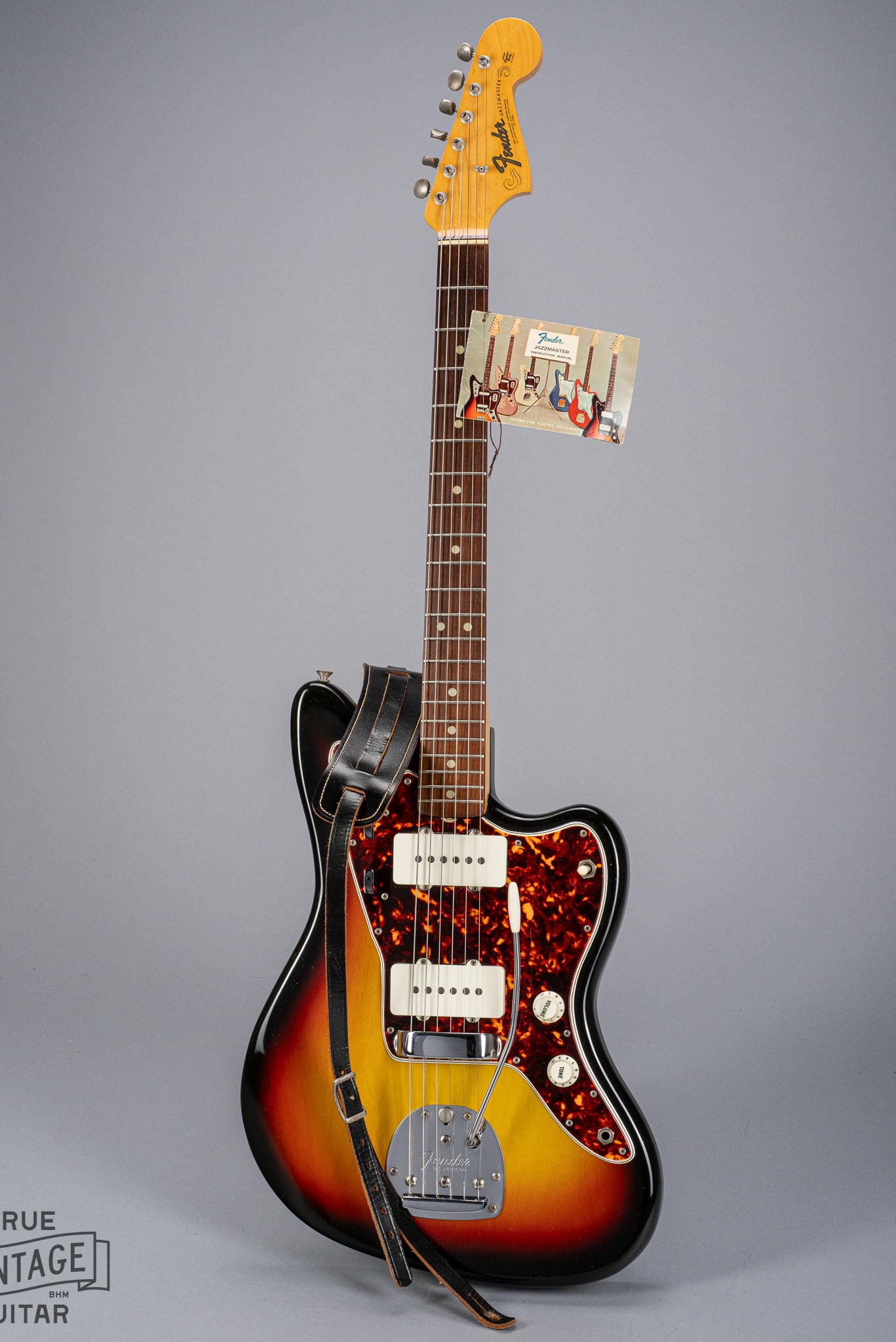 Front of 1965 Fender Jazzmaster sunburst guitar original hangtag and original strap