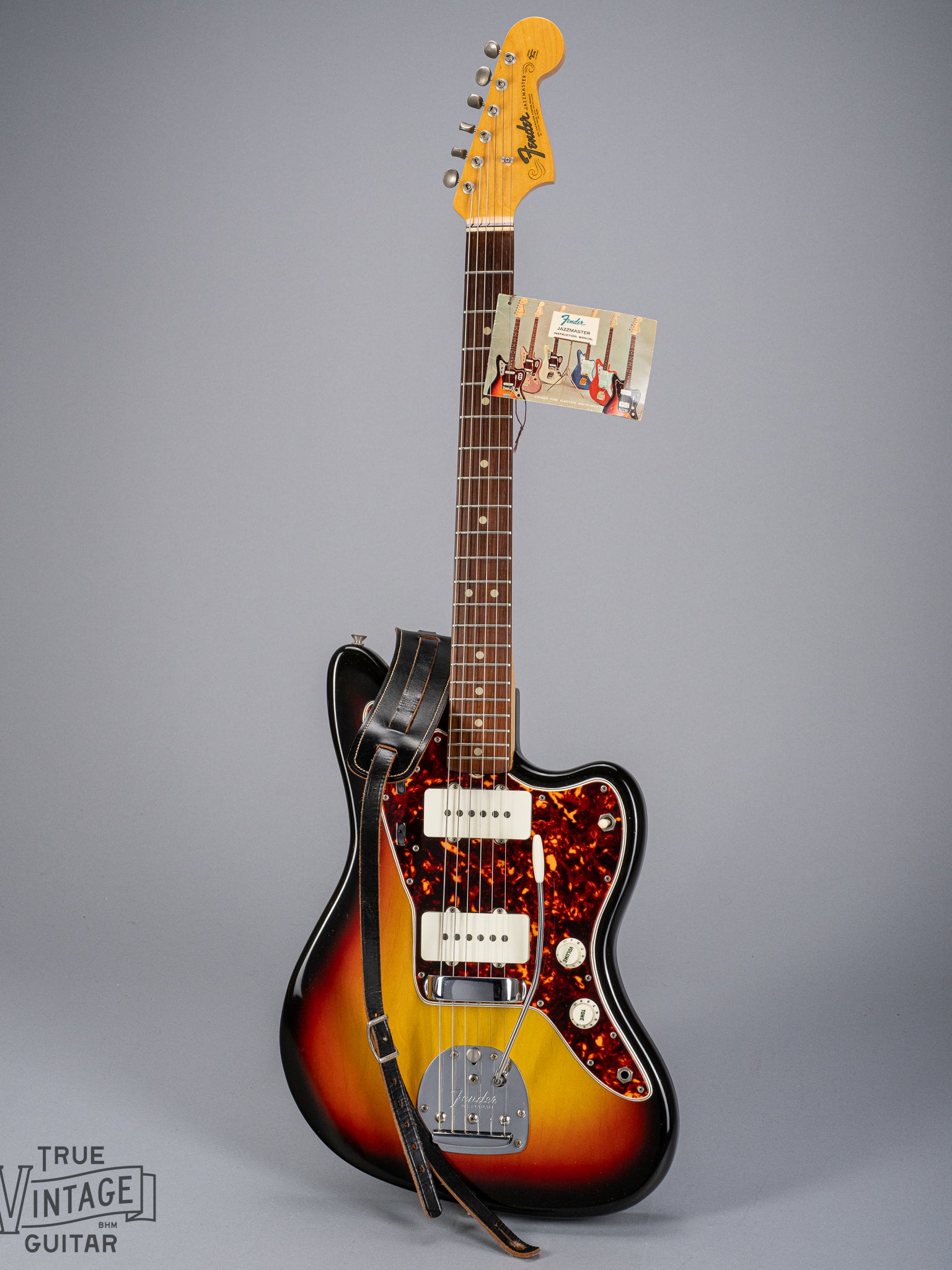 Front of 1965 Fender Jazzmaster sunburst guitar original hangtag and original strap