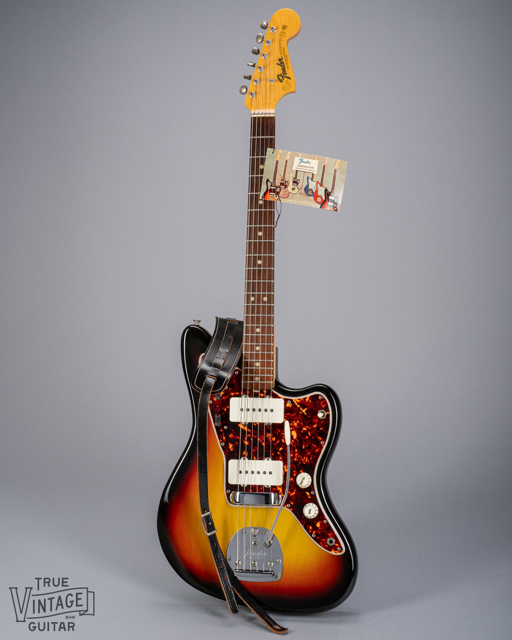 Front of 1965 Fender Jazzmaster sunburst guitar original hangtag and original strap