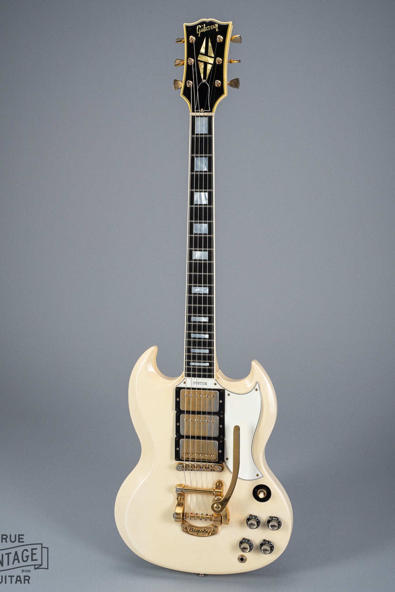 Front of 1965 Gibson SG Custom white guitar three pickup bigsby volume and tone controls block inlays fretboard binding gold neck headstock tuners block inlays