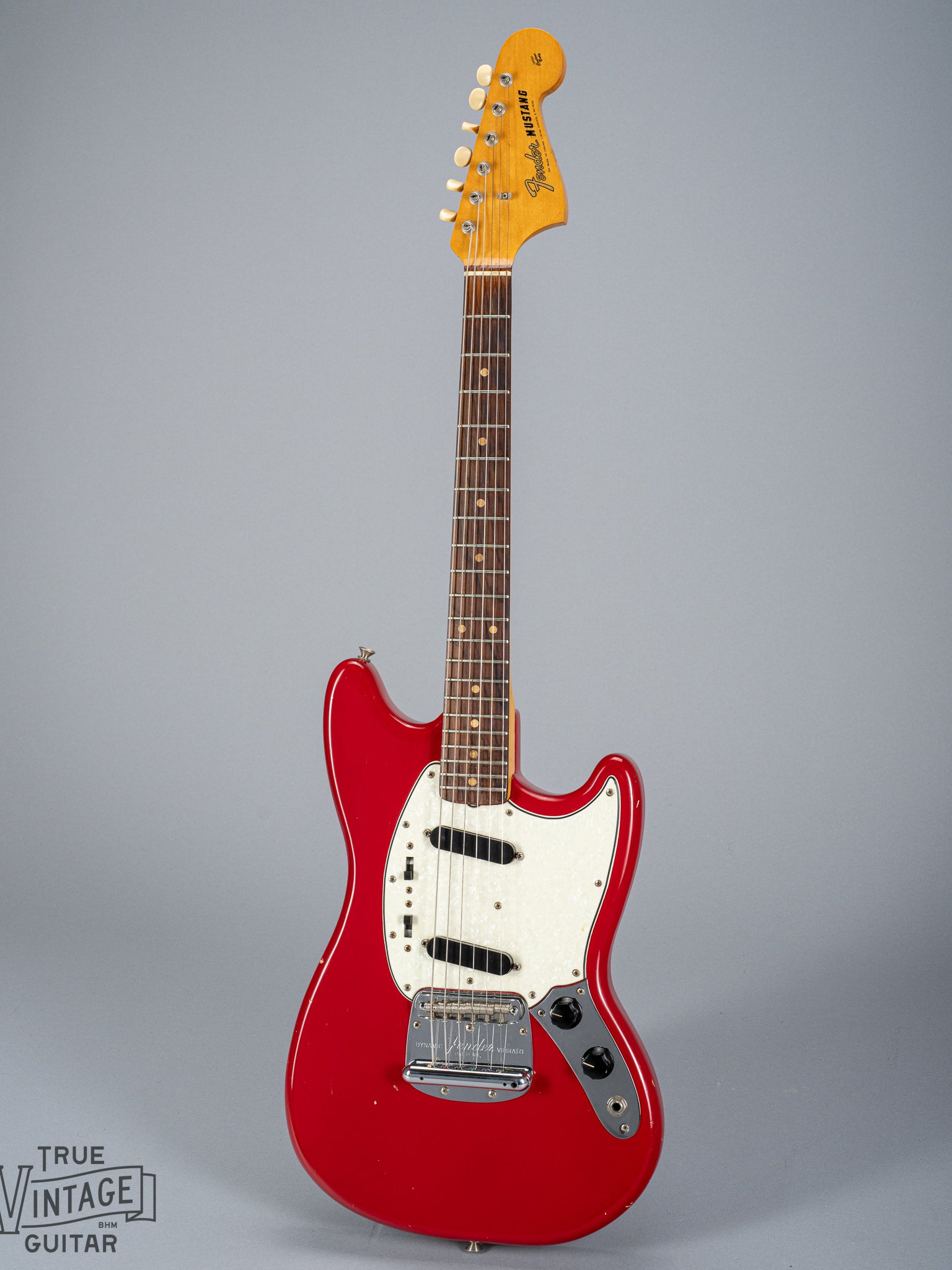 front of 1965 Fender Mustang Red guitar sparkle pick guard single coils original hardware neck fretboard headstock logo tuning buttons