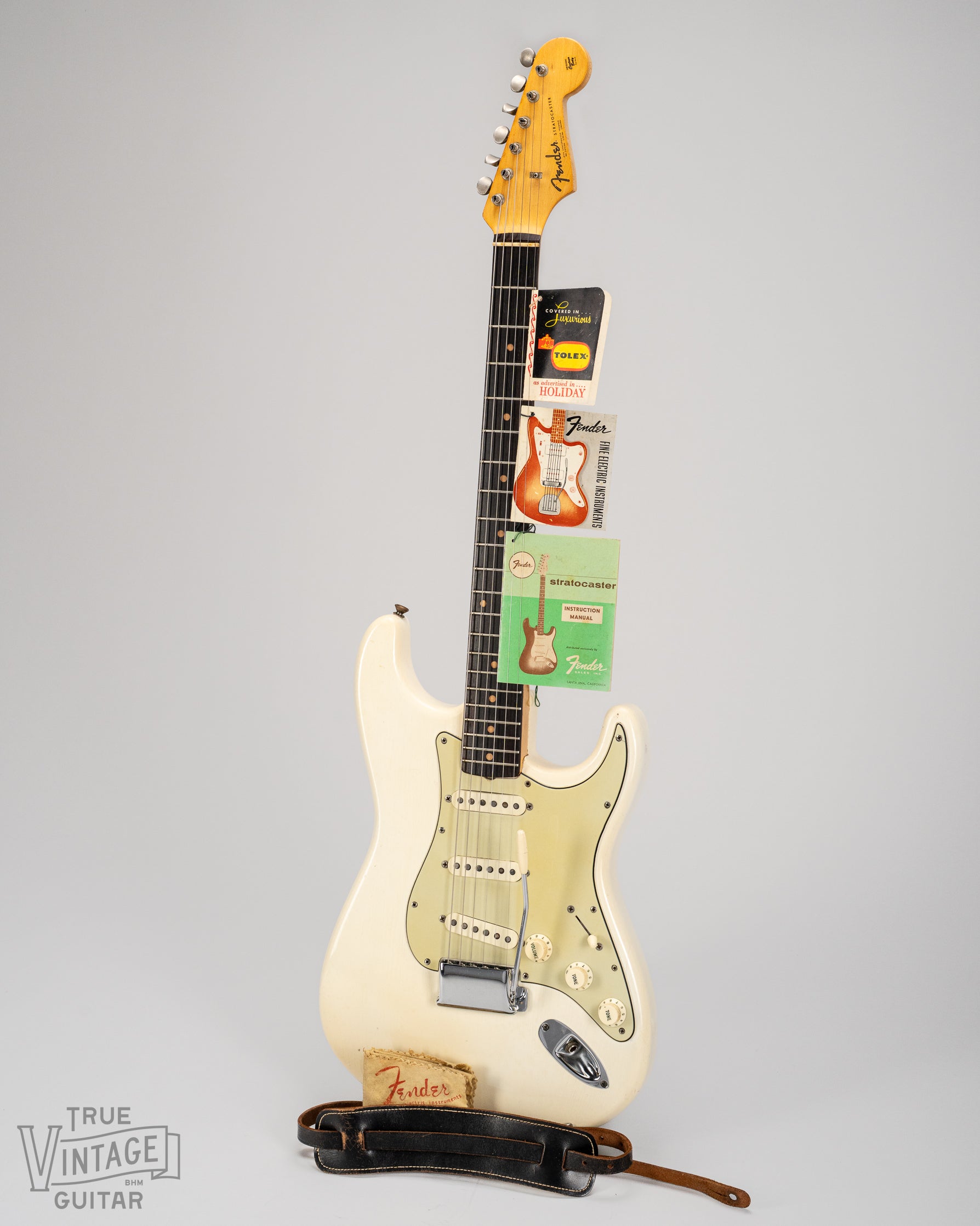 1962 Fender Stratocaster Olympic White guitar with hang tags, instruction manual, strap, and polish cloth.